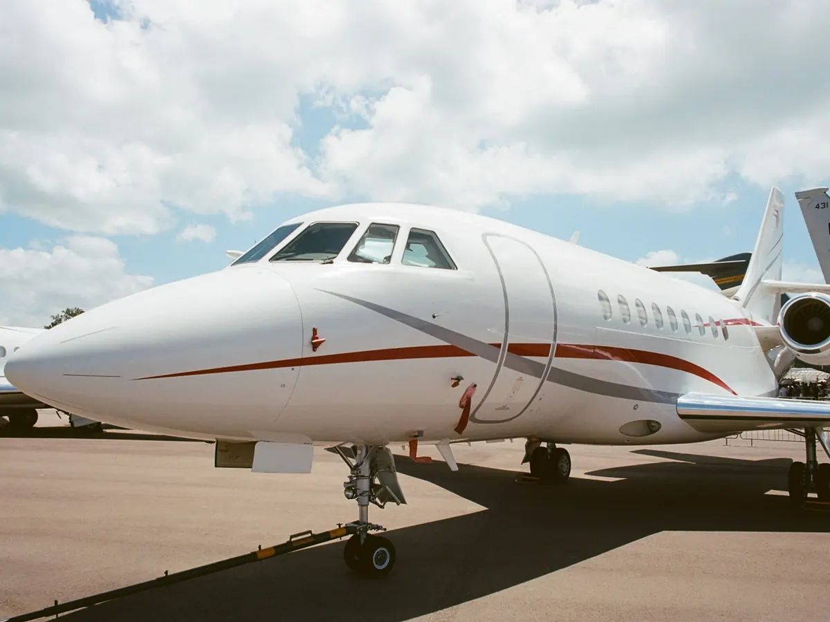 The nose of a white business jet on a sunny ramp