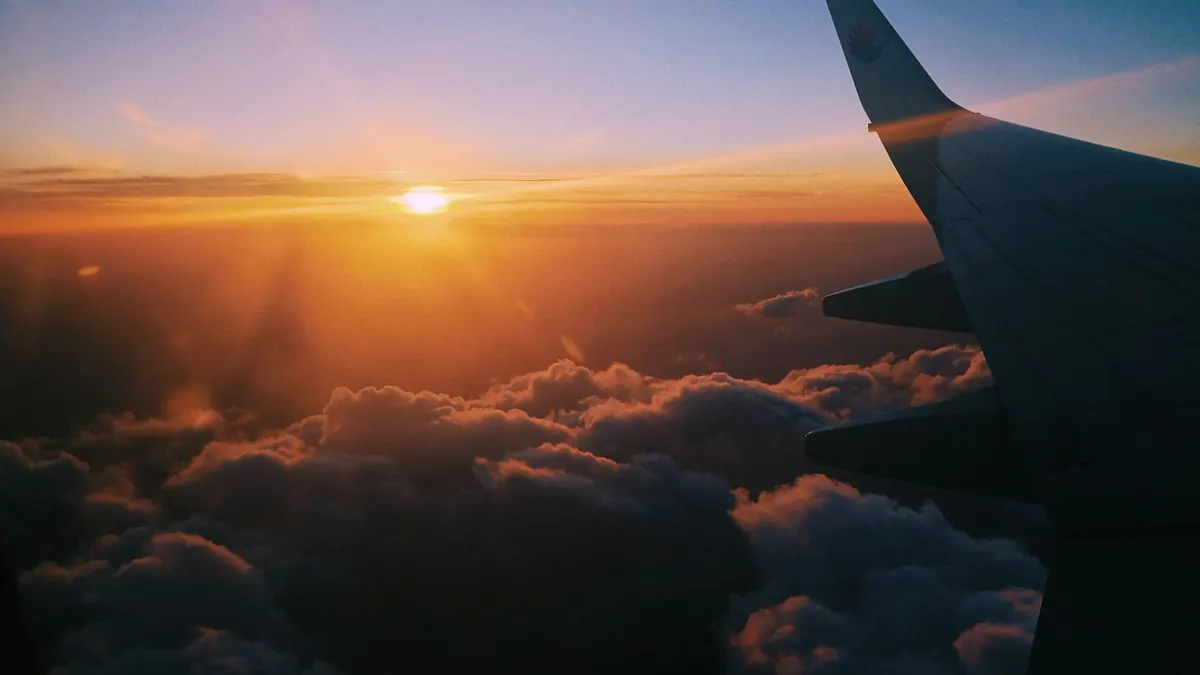 An aircraft wing above the clouds at sunset